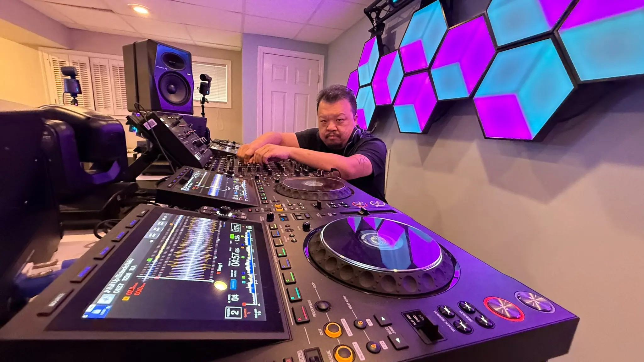 dejafua looking toward the camera with the mixer and CDJs visible